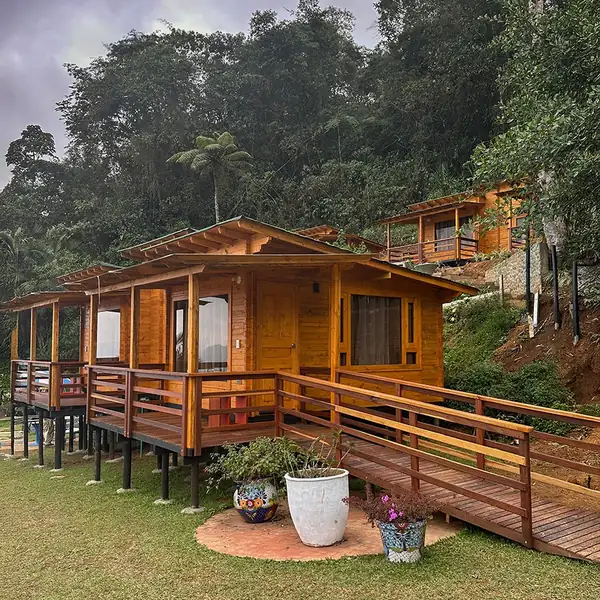 Cabaña de madera sobre pilotes rodeada de jardín y bosque
